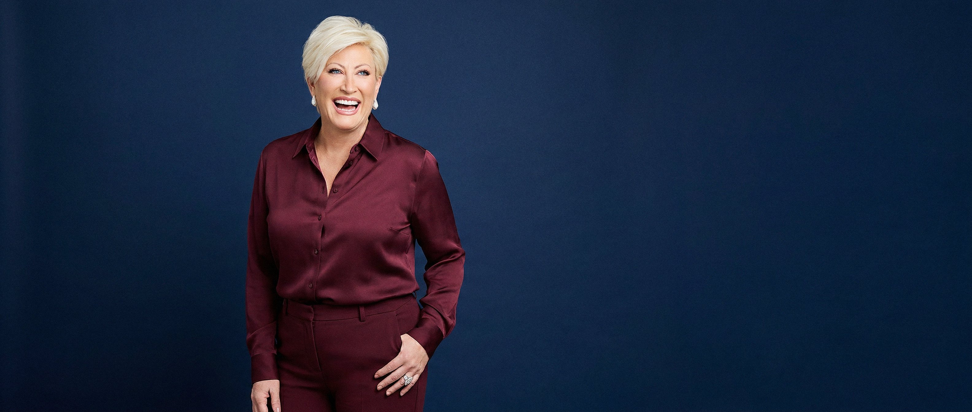 Kim Gravel in a burgundy suit against a royal blue backdrop