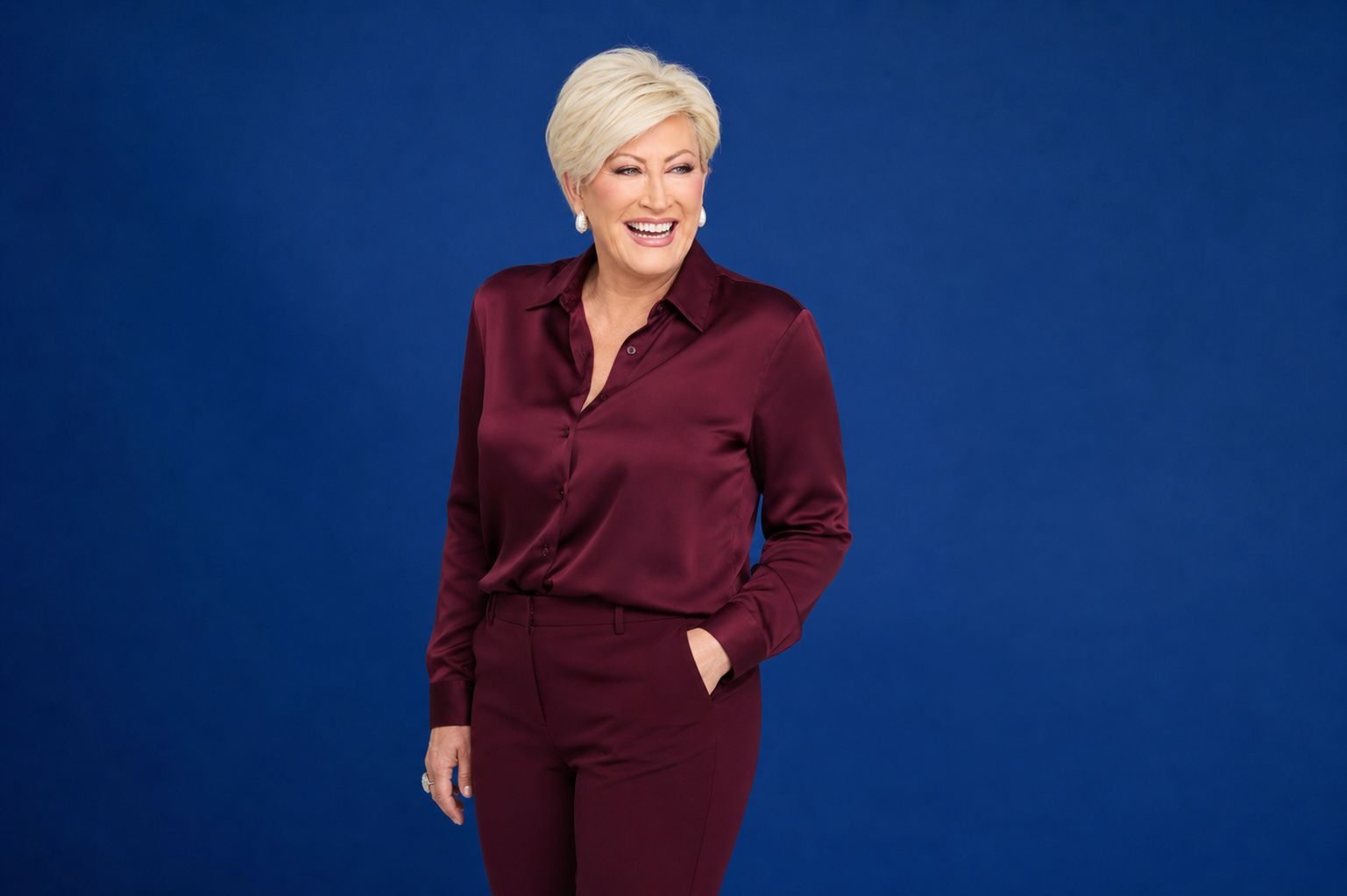 Kim Gravel in a burgundy suit against a royal blue backdrop