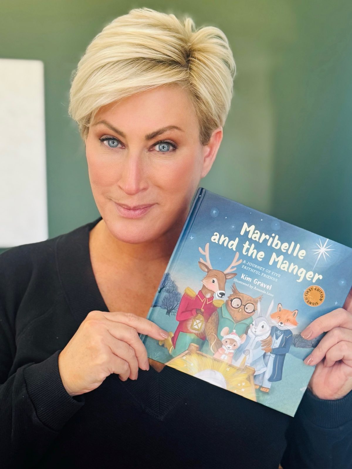 Kim Gravel holding a signed first edition of Maribelle and the Manger